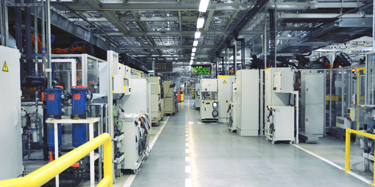 Automated factory production line with rows of industrial machinery and robotic arms along a central walkway.